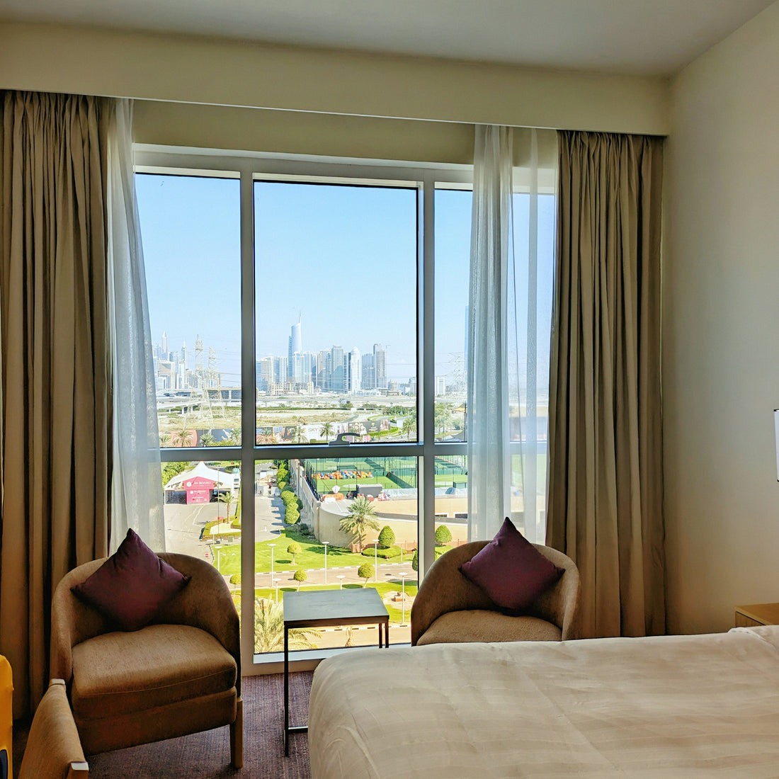 Elegant bedroom with blackout curtains framing a large window and city view.