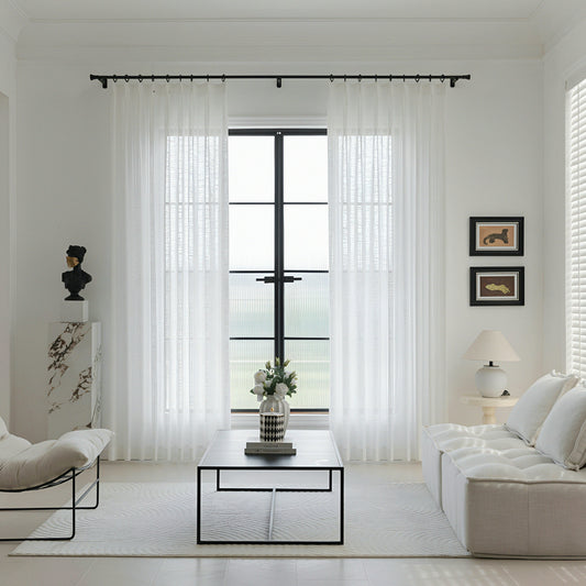 Modern living room with white sheer curtains allowing soft natural light through large window