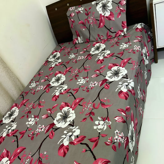 Pink floral bedsheet with white blossoms on grey background, styled on a single bed — Marjan3x UAE